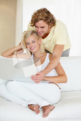 Image of Happy, laptop and young couple on sofa browsing on social media or the internet at apartment. Smile, technology and man and woman relax and researching on website with computer in living room at home