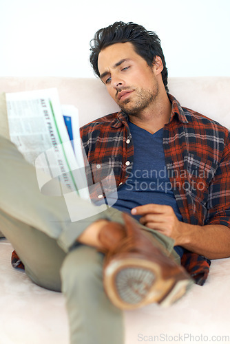 Image of Man, relax and reading a newspaper on couch in home, living room and learning about event from media. Calm, weekend and person with news, paper or article on sofa in apartment with information