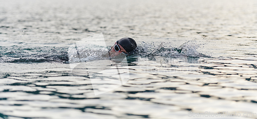 Image of A professional triathlete trains with unwavering dedication for an upcoming competition at a lake, emanating a sense of athleticism and profound commitment to excellence.