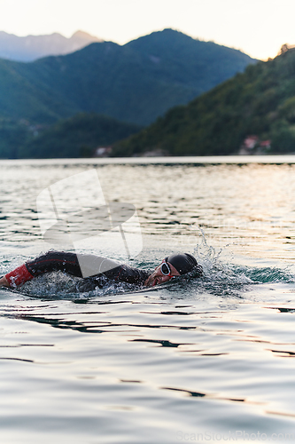 Image of A professional triathlete trains with unwavering dedication for an upcoming competition at a lake, emanating a sense of athleticism and profound commitment to excellence.