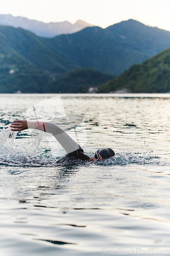 Image of A professional triathlete trains with unwavering dedication for an upcoming competition at a lake, emanating a sense of athleticism and profound commitment to excellence.