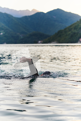 Image of A professional triathlete trains with unwavering dedication for an upcoming competition at a lake, emanating a sense of athleticism and profound commitment to excellence.