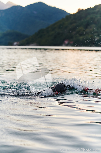 Image of A professional triathlete trains with unwavering dedication for an upcoming competition at a lake, emanating a sense of athleticism and profound commitment to excellence.