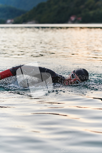 Image of A professional triathlete trains with unwavering dedication for an upcoming competition at a lake, emanating a sense of athleticism and profound commitment to excellence.