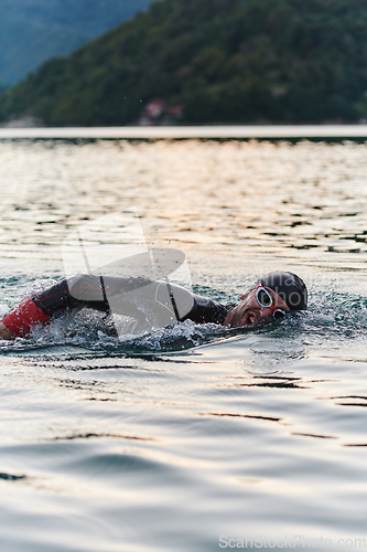 Image of A professional triathlete trains with unwavering dedication for an upcoming competition at a lake, emanating a sense of athleticism and profound commitment to excellence.