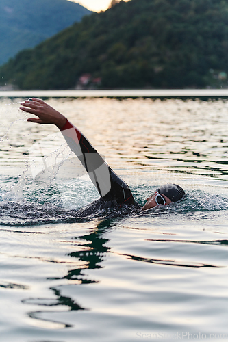 Image of A professional triathlete trains with unwavering dedication for an upcoming competition at a lake, emanating a sense of athleticism and profound commitment to excellence.