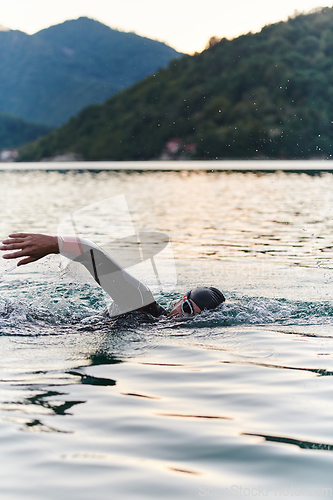 Image of A professional triathlete trains with unwavering dedication for an upcoming competition at a lake, emanating a sense of athleticism and profound commitment to excellence.