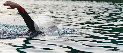 Image of A professional triathlete trains with unwavering dedication for an upcoming competition at a lake, emanating a sense of athleticism and profound commitment to excellence.