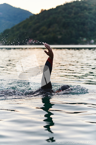 Image of A professional triathlete trains with unwavering dedication for an upcoming competition at a lake, emanating a sense of athleticism and profound commitment to excellence.