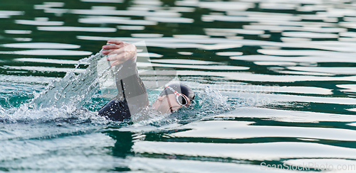 Image of A professional triathlete trains with unwavering dedication for an upcoming competition at a lake, emanating a sense of athleticism and profound commitment to excellence.