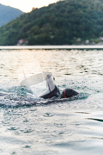 Image of A professional triathlete trains with unwavering dedication for an upcoming competition at a lake, emanating a sense of athleticism and profound commitment to excellence.