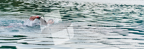 Image of A professional triathlete trains with unwavering dedication for an upcoming competition at a lake, emanating a sense of athleticism and profound commitment to excellence.