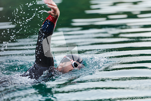 Image of A professional triathlete trains with unwavering dedication for an upcoming competition at a lake, emanating a sense of athleticism and profound commitment to excellence.