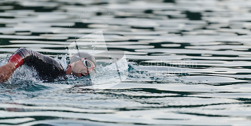 Image of A professional triathlete trains with unwavering dedication for an upcoming competition at a lake, emanating a sense of athleticism and profound commitment to excellence.