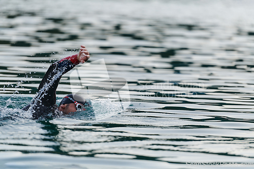 Image of A professional triathlete trains with unwavering dedication for an upcoming competition at a lake, emanating a sense of athleticism and profound commitment to excellence.