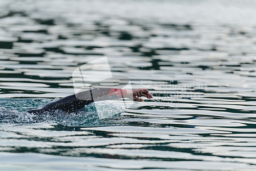 Image of A professional triathlete trains with unwavering dedication for an upcoming competition at a lake, emanating a sense of athleticism and profound commitment to excellence.