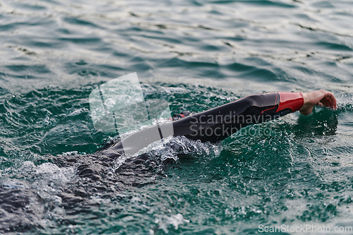 Image of A professional triathlete trains with unwavering dedication for an upcoming competition at a lake, emanating a sense of athleticism and profound commitment to excellence.