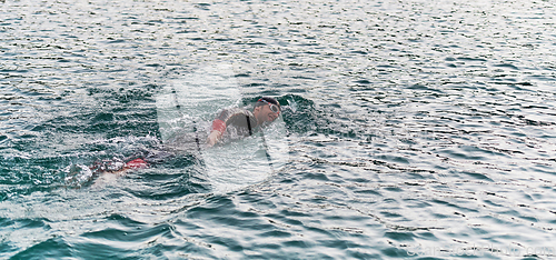 Image of A professional triathlete trains with unwavering dedication for an upcoming competition at a lake, emanating a sense of athleticism and profound commitment to excellence.