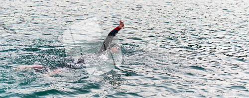 Image of A professional triathlete trains with unwavering dedication for an upcoming competition at a lake, emanating a sense of athleticism and profound commitment to excellence.