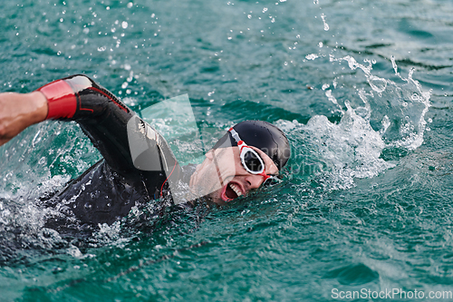 Image of A professional triathlete trains with unwavering dedication for an upcoming competition at a lake, emanating a sense of athleticism and profound commitment to excellence.