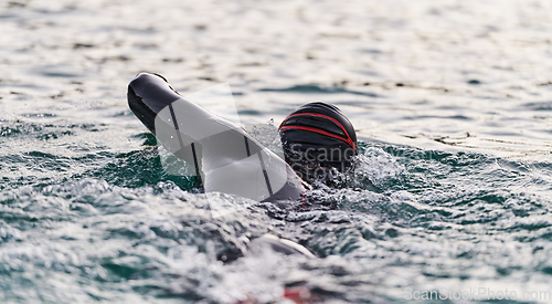 Image of A professional triathlete trains with unwavering dedication for an upcoming competition at a lake, emanating a sense of athleticism and profound commitment to excellence.