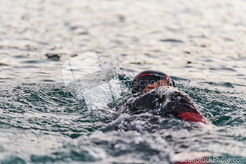 Image of A professional triathlete trains with unwavering dedication for an upcoming competition at a lake, emanating a sense of athleticism and profound commitment to excellence.