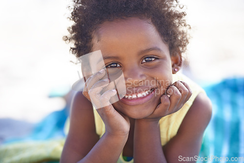 Image of Happy, african child and portrait on beach sand, relax and summer holiday with sunshine in nature. Black girl, young and smile face on towel on vacation, cape town and seaside for wellness in outdoor