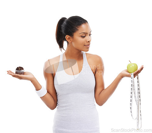 Image of Fitness, woman and choice of an apple or cupcake in studio isolated on a white background for weight loss. Exercise, fruit and measuring tape with a young athlete holding health options for decision