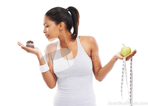 Image of Woman, cupcake and choice or fruit decision in studio healthy, nutrition benefits or weight loss. Female person, dessert and apple in hands for balance or mockup space, wellness or white background