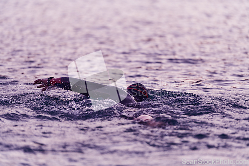 Image of A professional triathlete trains with unwavering dedication for an upcoming competition at a lake, emanating a sense of athleticism and profound commitment to excellence.