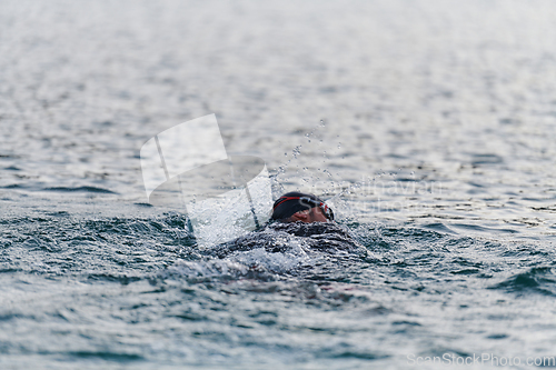 Image of A professional triathlete trains with unwavering dedication for an upcoming competition at a lake, emanating a sense of athleticism and profound commitment to excellence.