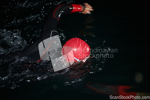 Image of A determined professional triathlete undergoes rigorous night time training in cold waters, showcasing dedication and resilience in preparation for an upcoming triathlon swim competition