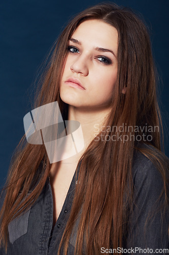 Image of Portrait, beauty and a serious young woman in studio on a dark background with an intense attitude. Face, skincare and makeup with a fierce model looking confident in cosmetic wellness or haircare