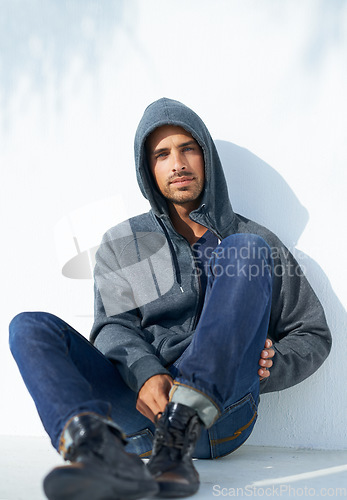 Image of Fashion, serious and portrait of man by a wall with casual, cool and stylish outfit with confidence. Handsome, young and young male person with trendy style with jeans and hoodie by white background.