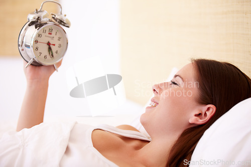 Image of Alarm, clock and happy woman in a bed with morning, alert or bell ring for start of day or routine in her home. Time, wake up and female person smile in a bedroom after peaceful sleep, nap or resting