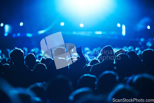 Image of People, blue and crowd for concert, performance or stage in arena for rock, psychedelic or electric music. Lens flare, light and equipment with person, holding and smartphone for social media post