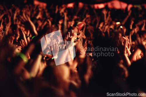 Image of People, hands and crowd for music, festival and outside with arms raised for dancing, movement or enjoyment. Audience, concert and excitement with dj, band or singer with red, lighting and equipment