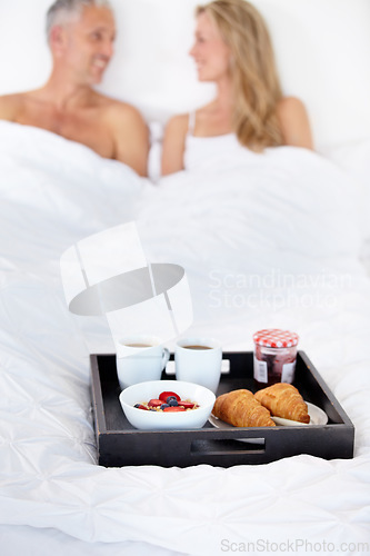 Image of Happy couple, bed and breakfast for morning, wakeup or room service in romance at hotel suite. Man and woman smile with food, meal or snack tray in bedroom of jam jar croissant, coffee or fruit salad