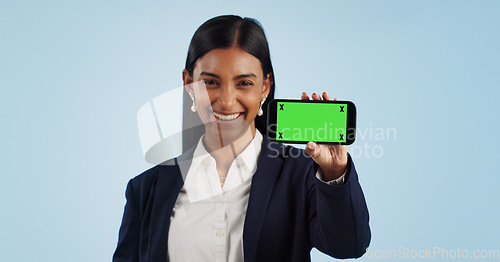 Image of Happy business woman, phone and green screen for advertising against a blue studio background. Portrait of female person or employee smile showing mobile smartphone display, chromakey or mockup space