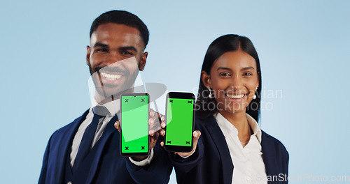 Image of Business people, portrait and phone with green screen for advertising against a blue studio background. Businessman and woman employee showing mobile smartphone display, chromakey or mockup space