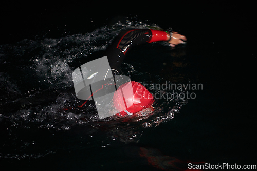 Image of A determined professional triathlete undergoes rigorous night time training in cold waters, showcasing dedication and resilience in preparation for an upcoming triathlon swim competition