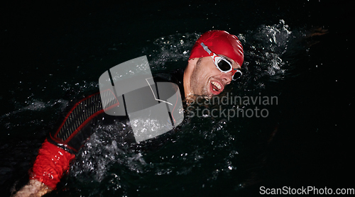 Image of A determined professional triathlete undergoes rigorous night time training in cold waters, showcasing dedication and resilience in preparation for an upcoming triathlon swim competition