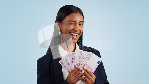 Image of Business woman, portrait and wink with money fan in financial freedom against a blue studio background. Female person or employee with cash, savings or investment for bonus salary on mockup space