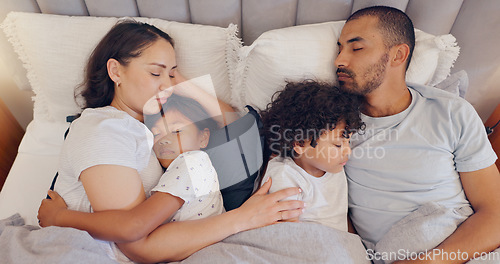 Image of Tired, sleeping and parents with children in bed on a weekend morning in modern family home. Exhausted, cuddle and young mother and father taking a nap and dreaming with kids in bedroom at house.