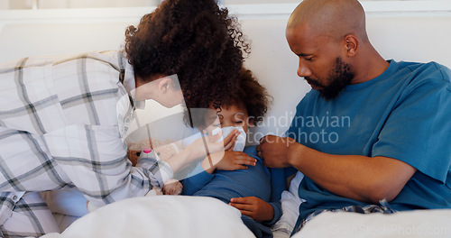 Image of Mother, father and sick child in bed blowing nose for virus, infection or disease in care or support at home. Mom, dad and kid with flu, cold or symptoms for allergies, sinus or morning in bedroom