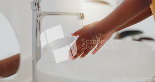 Image of Child, tap and washing hands in water for hygiene, cleaning or bacteria or germ removal in sink at home. Closeup of kid rinsing soap in bathroom basin for disinfection, care or cleanliness at house