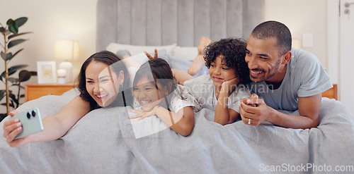 Image of Selfie, smile and children with parents in bed relaxing and bonding together at family home. Happy, fun and young mother and father laying and taking a picture with kids in bedroom of modern house.