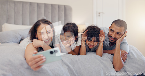 Image of Happy, selfie and children with parents in bed relaxing and bonding together at family home. Smile, fun and young mother and father laying and taking a picture with kids in bedroom of modern house.