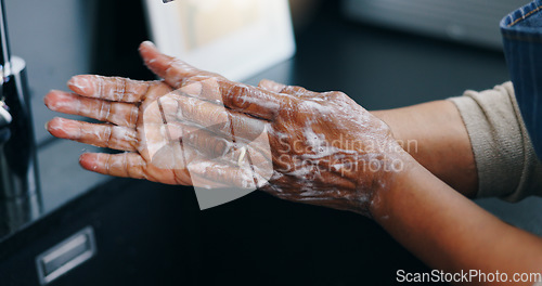 Image of Person, soap and washing hands for hygiene, germ or bacteria removal by tap or sink at home. Closeup of palm in skincare, protection or soapy skin for cleaning, dirt or disinfection by basin at house