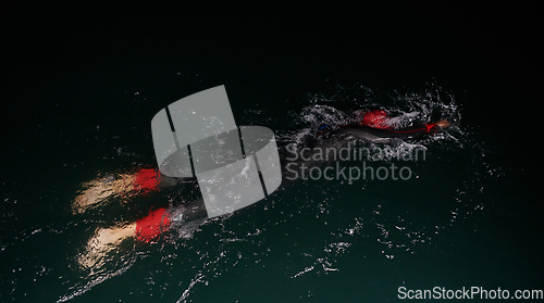 Image of A determined professional triathlete undergoes rigorous night time training in cold waters, showcasing dedication and resilience in preparation for an upcoming triathlon swim competition